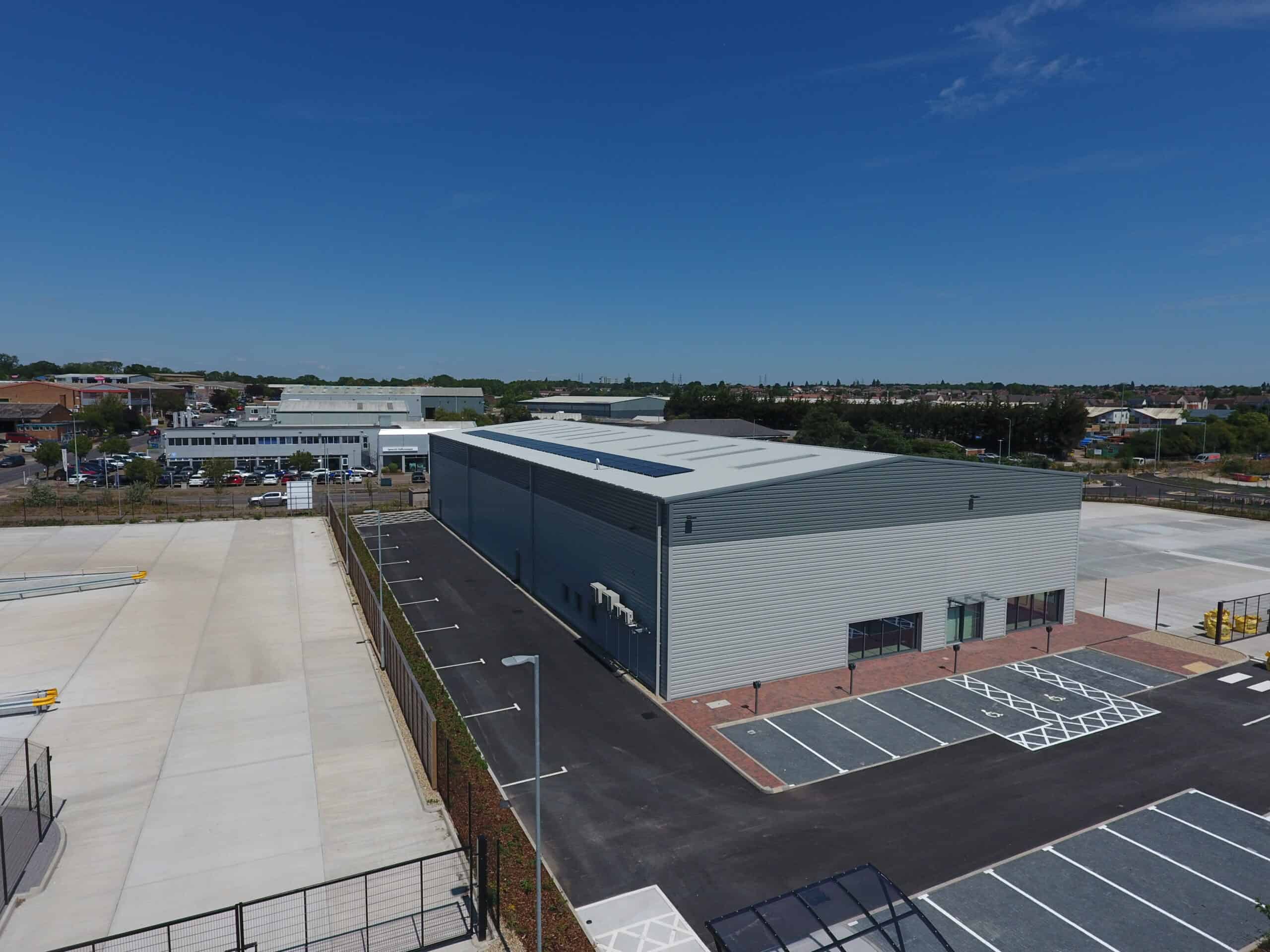 Looking Down On Commercial Warehouse Showing A Row Of Solar Panels On The Roof